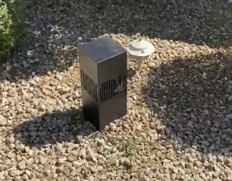 Landscape speaker installed in desert gravel beside a path light