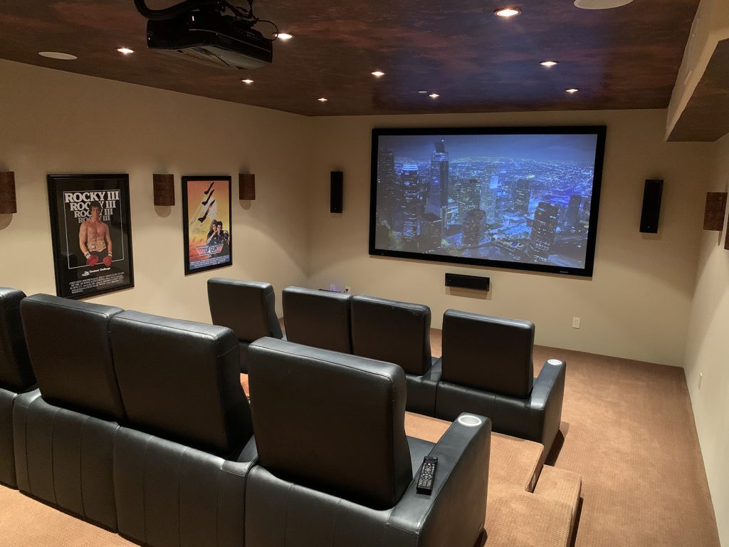 Completed home theater with projection screen, surround speakers and tiered leather seating