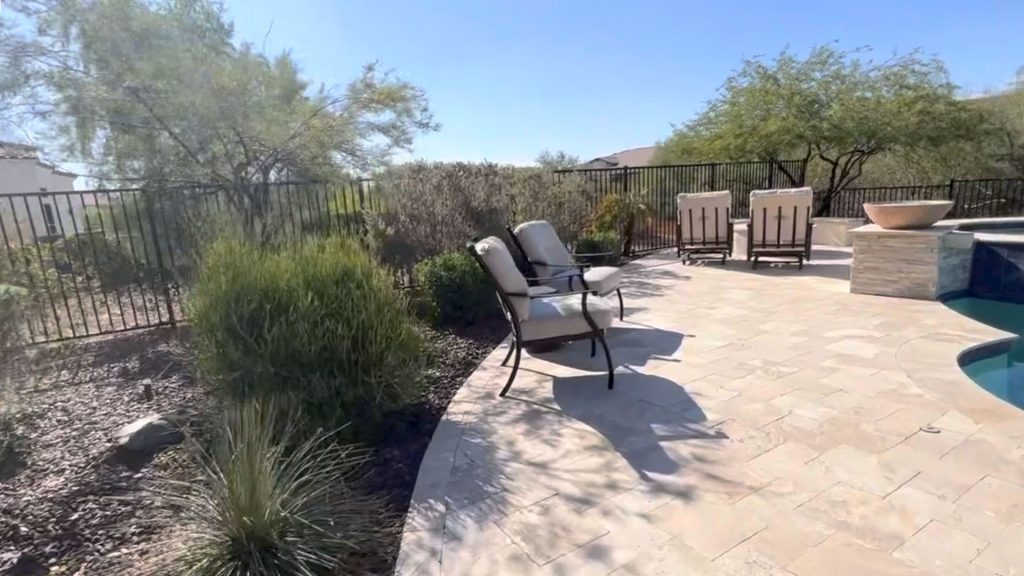 Rock-style outdoor speaker beside an Arizona pool patio and landscaped yard