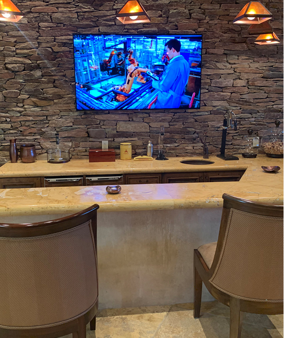 Integrated television and lighting in a stone-finished home bar