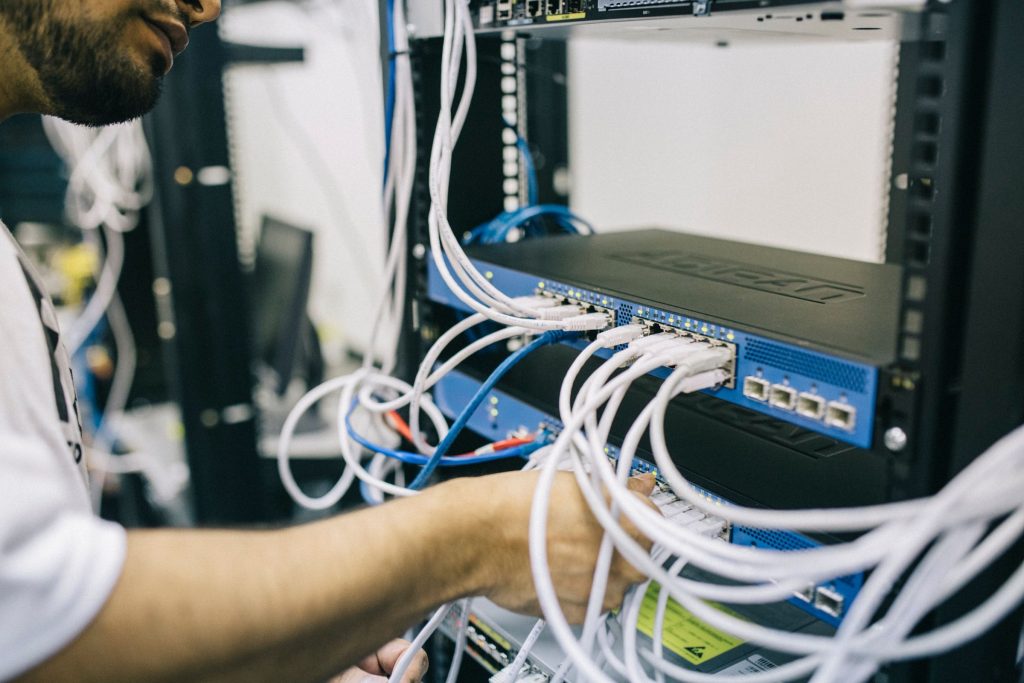 Low-voltage technician configuring structured network cabling in an equipment rack