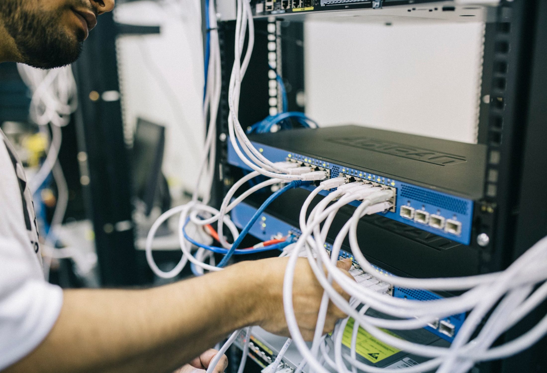 Low-voltage technician configuring structured network cabling in an equipment rack