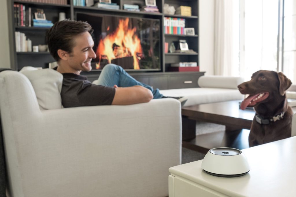 Homeowner relaxing with a Josh.ai voice-control device in a bright living room.